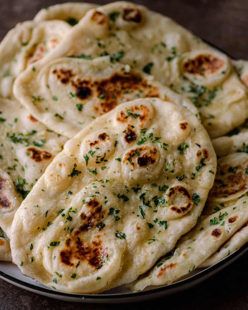 garlic butter vegan naan piled on a white plate