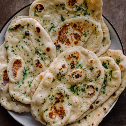 garlic butter vegan naan piled on a white plate