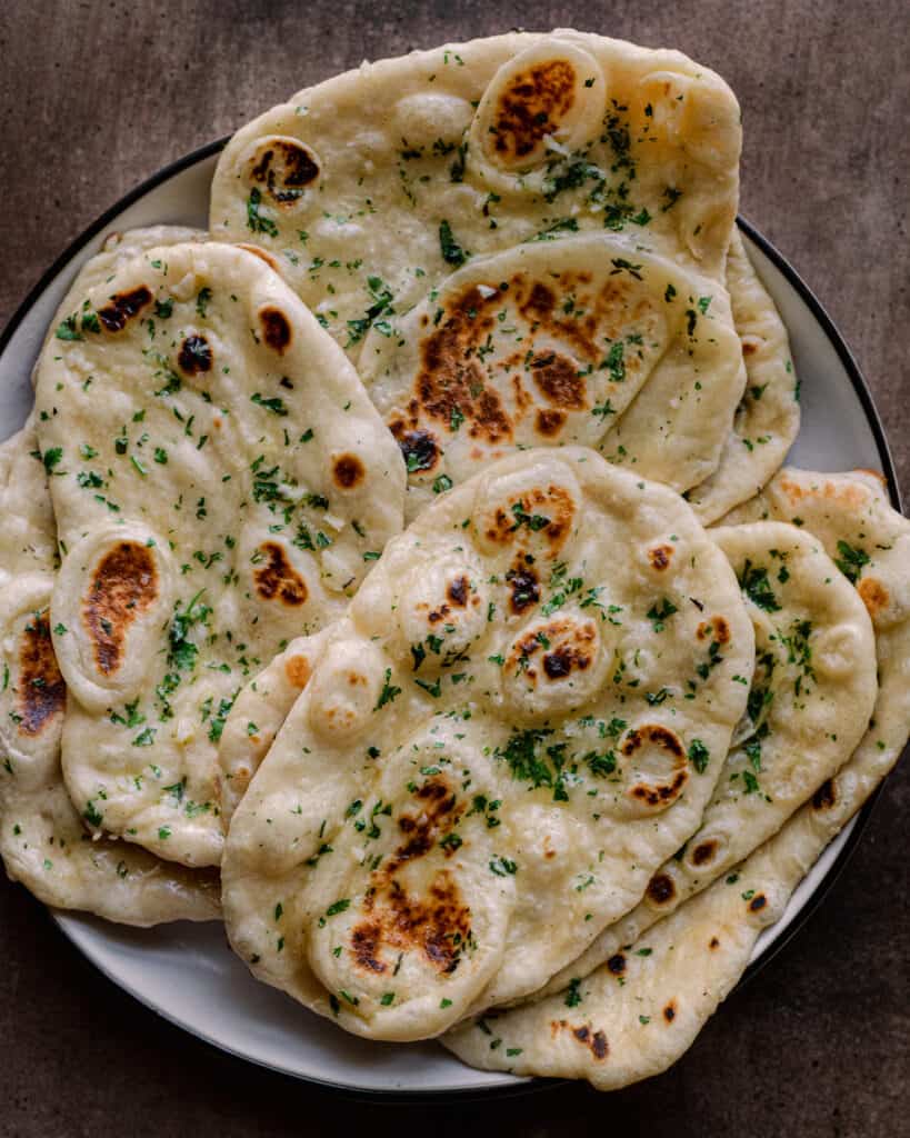 garlic butter vegan naan piled on a white plate