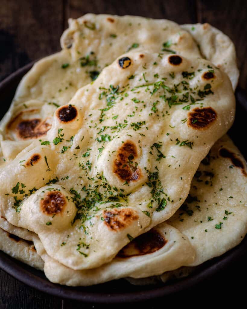 garlic butter vegan naan piled on a white plate