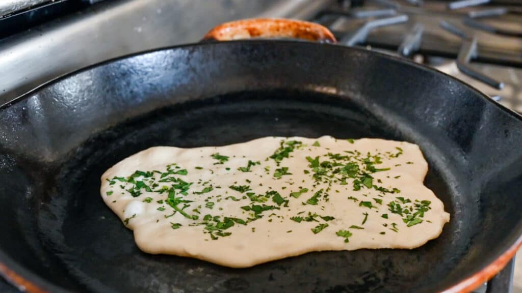 cilantro naan cooking in cast iron skillet