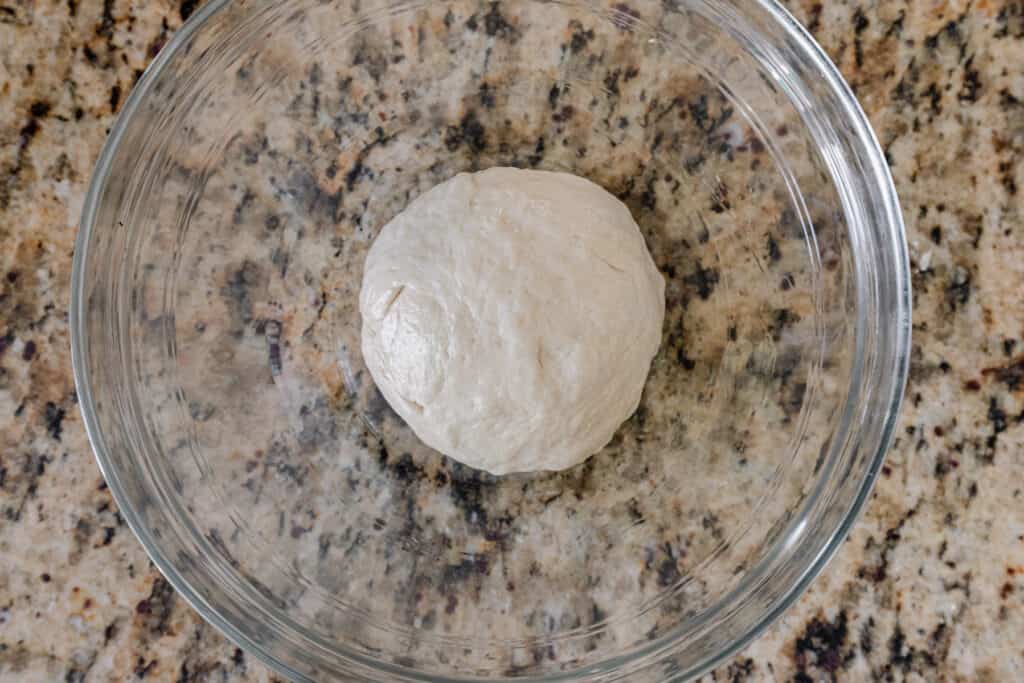 naan dough sitting in oiled bowl