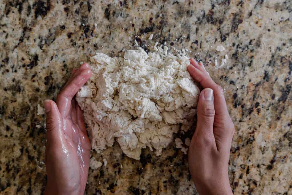 woman's hands about to knead a shaggy dough