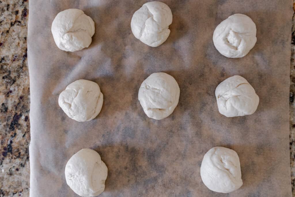 8 balls of naan dough on parchment paper