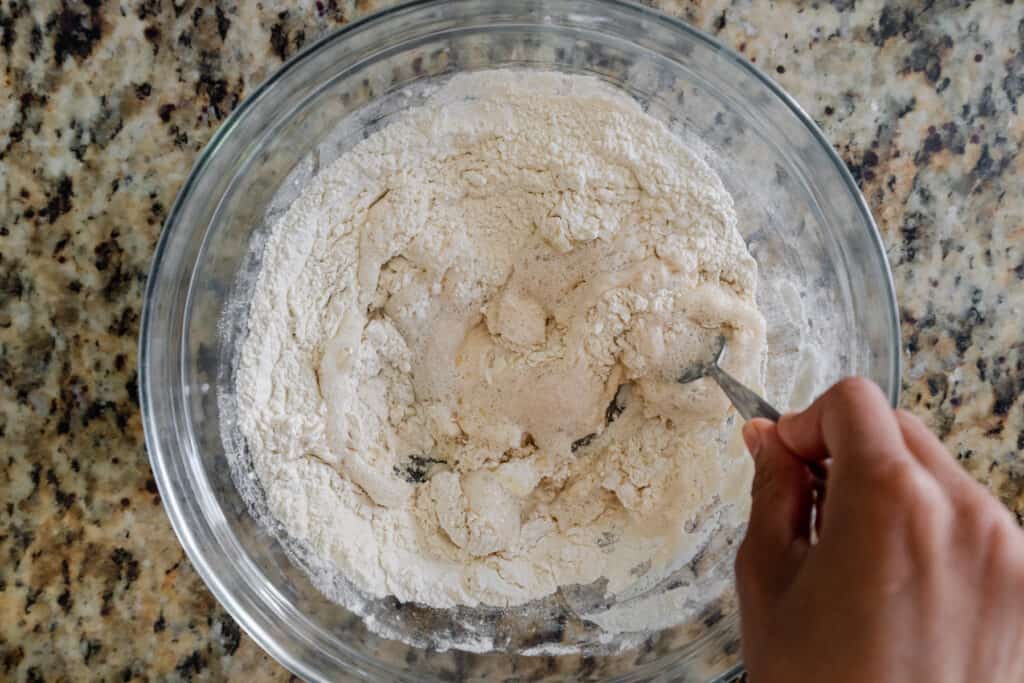 whisking yeast and water into flour