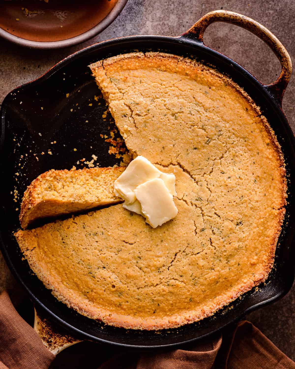 vegan cornbread in cast iron skillet with one slice turned up