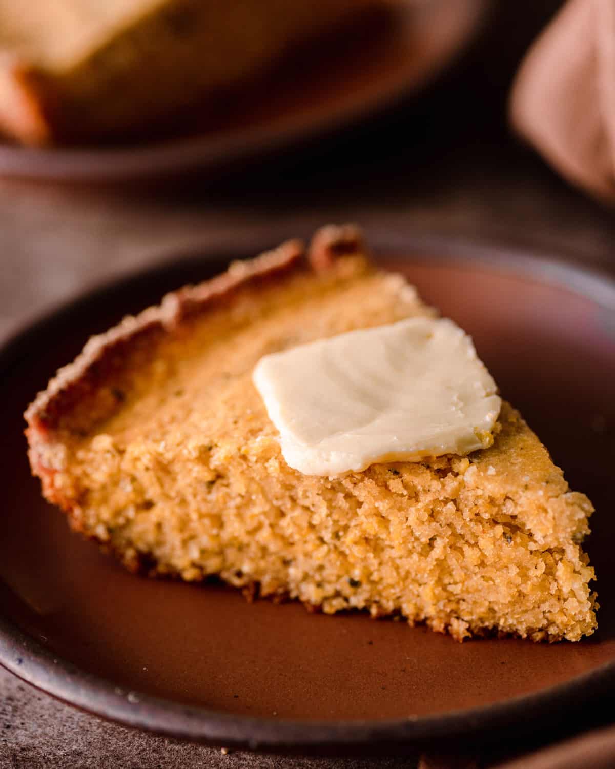 slice of vegan cornbread with a pat of butter on a plate