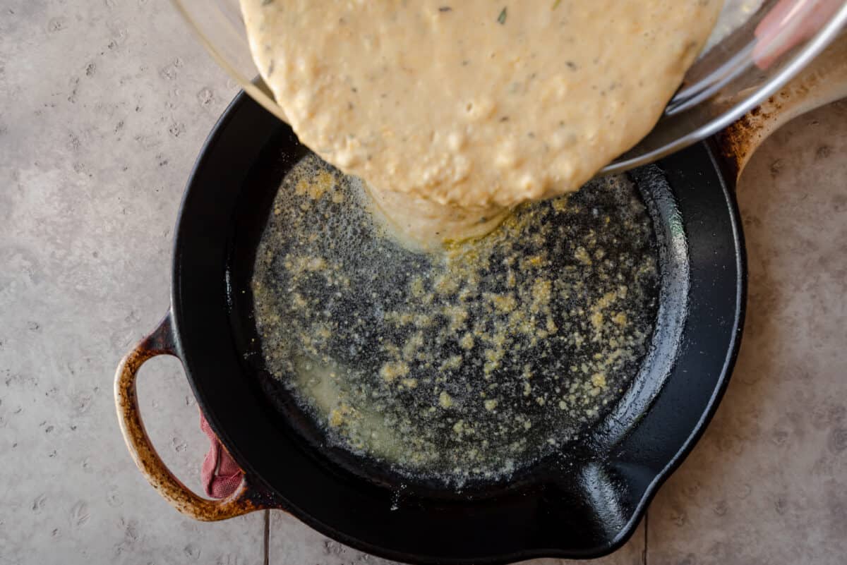 pouring cornbread batter into hot cast iron skillet