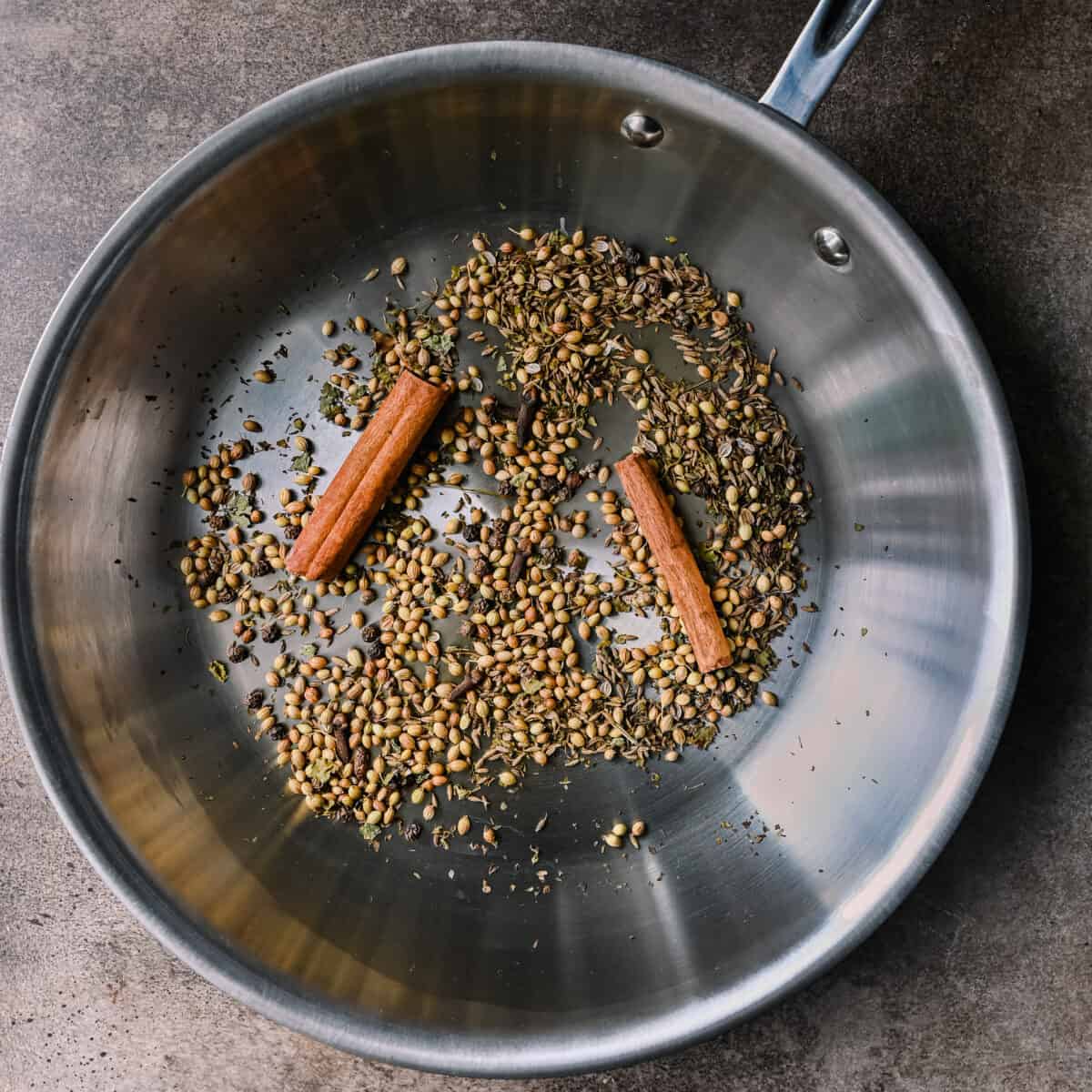 whole spices toasting in skillet