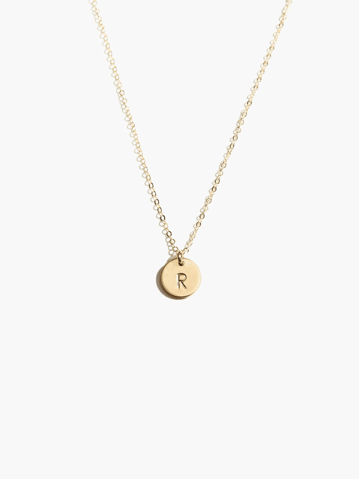 Gold necklace with an R on it.