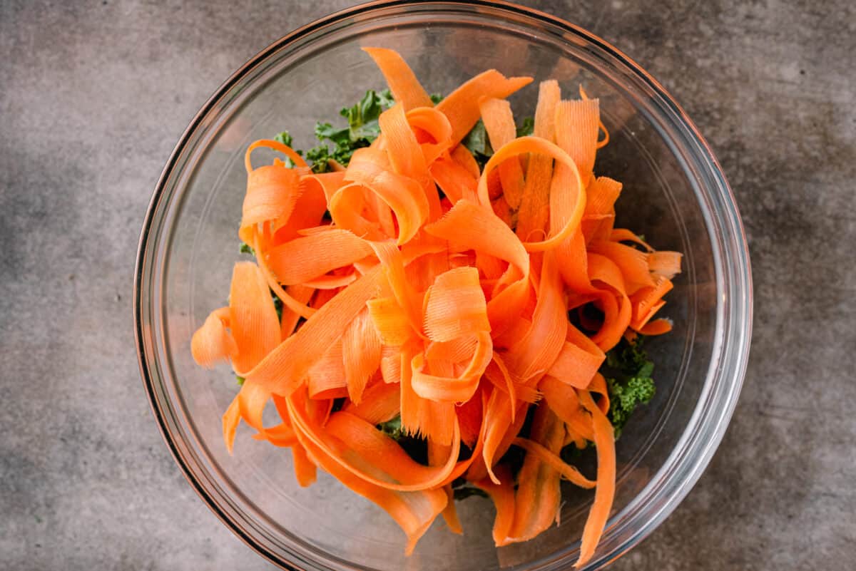 carrot ribbons on top of kale in bowl