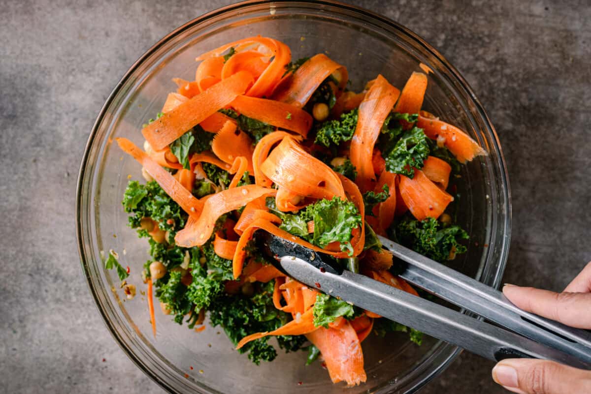tossing kale and carrot salad