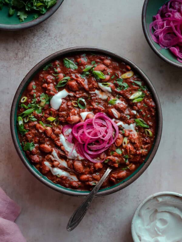 bowl of vegan chili with sour cream, cilantro and pickled onions