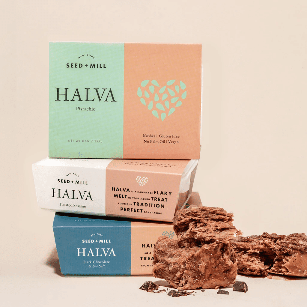 Boxes of halva stacked on each other with unboxed halva sitting in front of it as well.