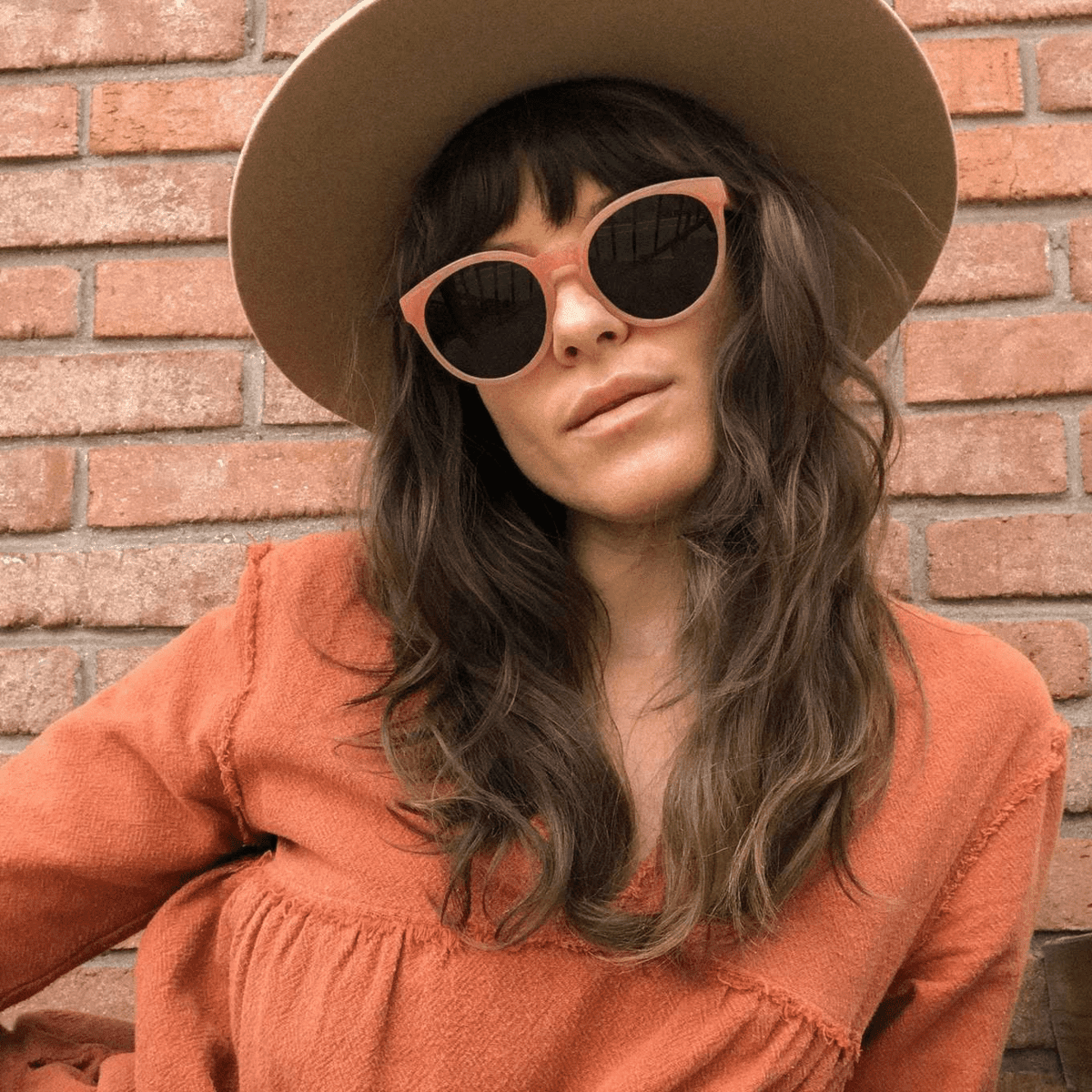 Woman wearing sunglasses and a tan wide-brimmed hat.