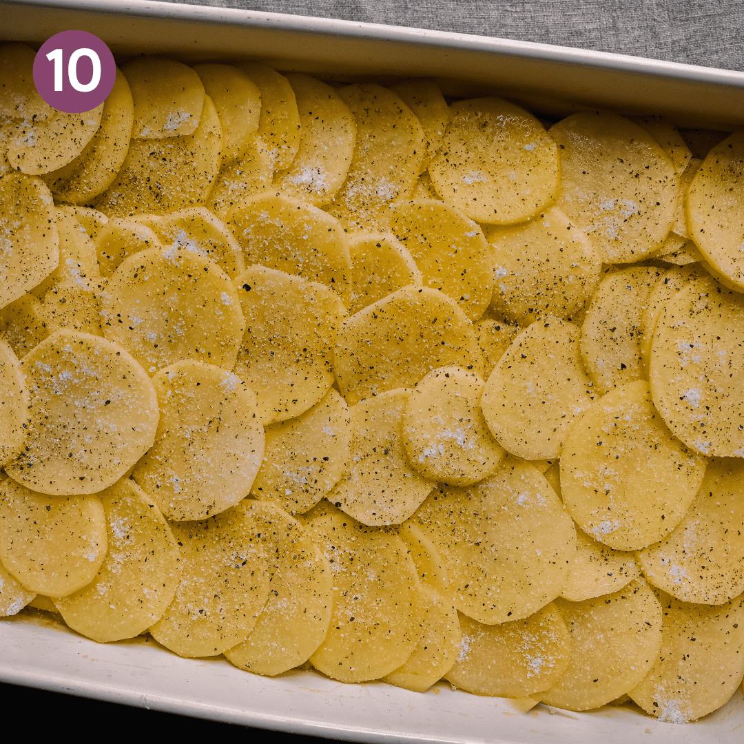 second layer of thinly sliced potatoes overlapping in a casserole pan for scalloped potatoes