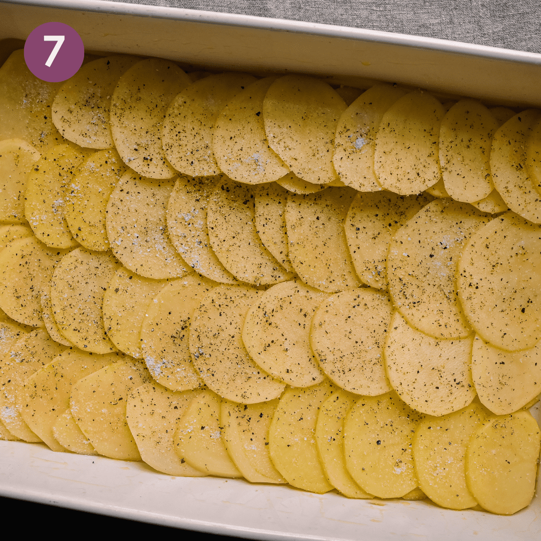layer of thinly sliced potatoes overlapping in a casserole pan for scalloped potatoes