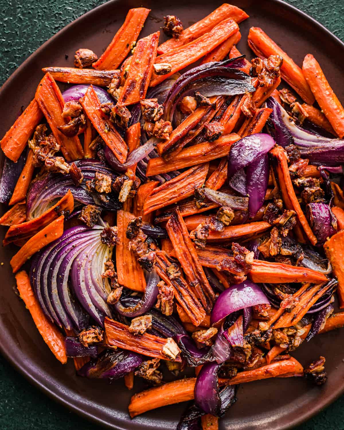 Carrots, dates and onions on a brown plate.