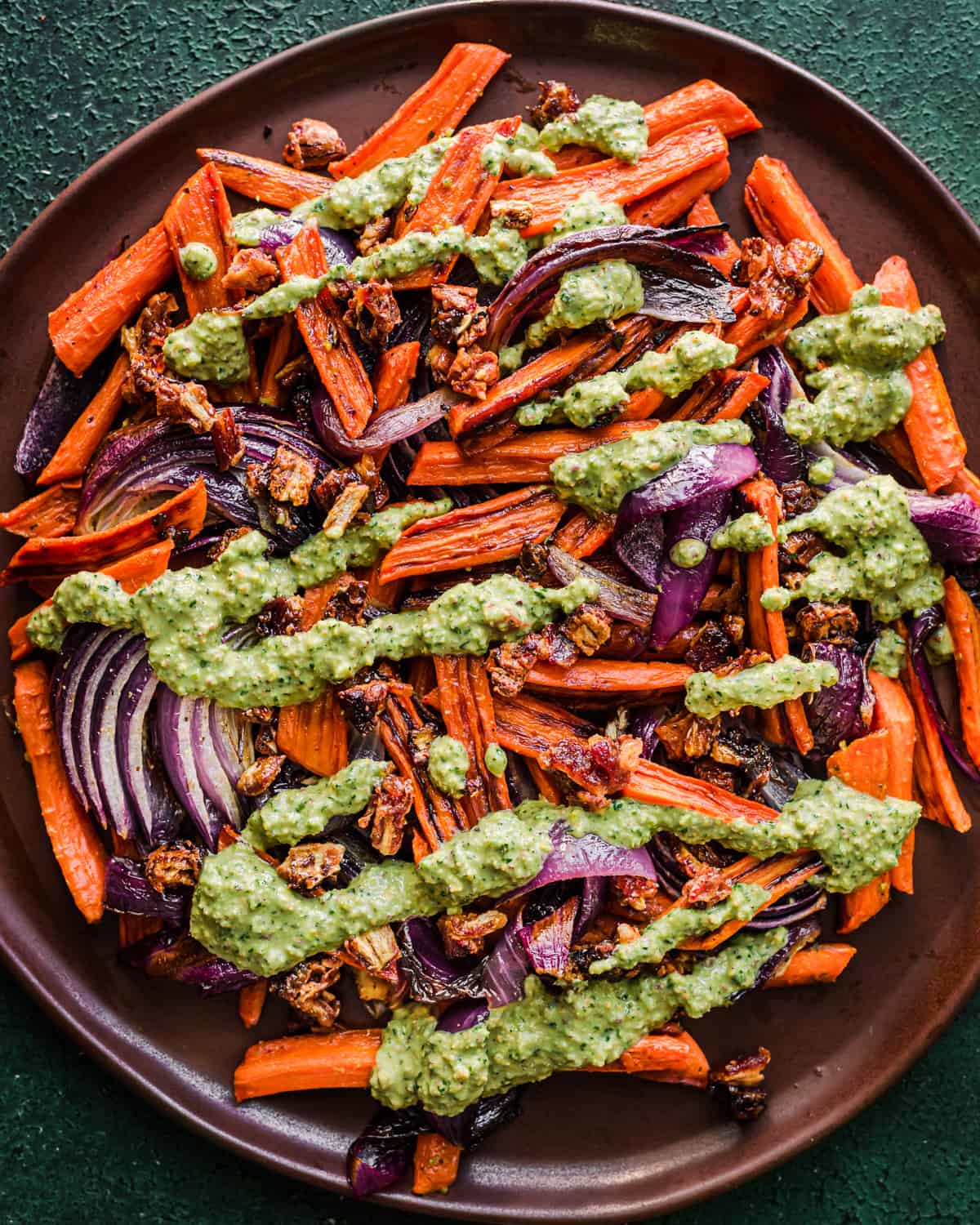 Pesto added to the carrots, onions and dates on a plate.