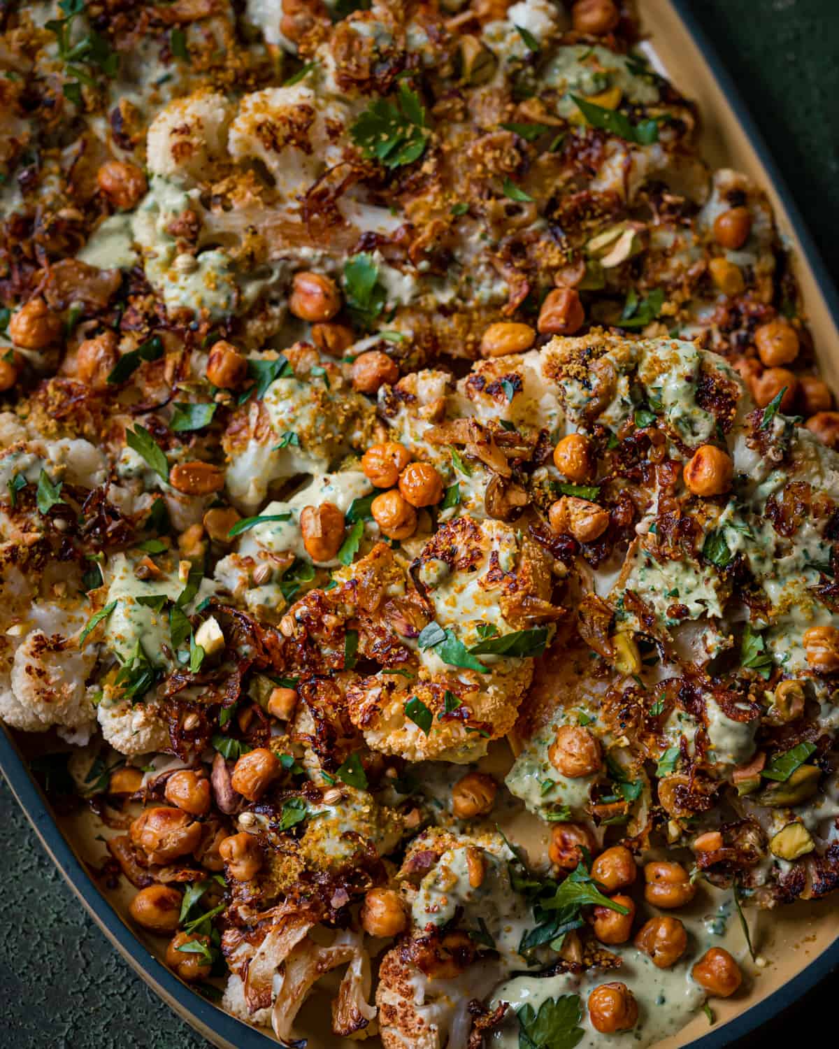 roasted cauliflower steaks and chickpeas with caramelized shallots and tahini sauce on yellow tray