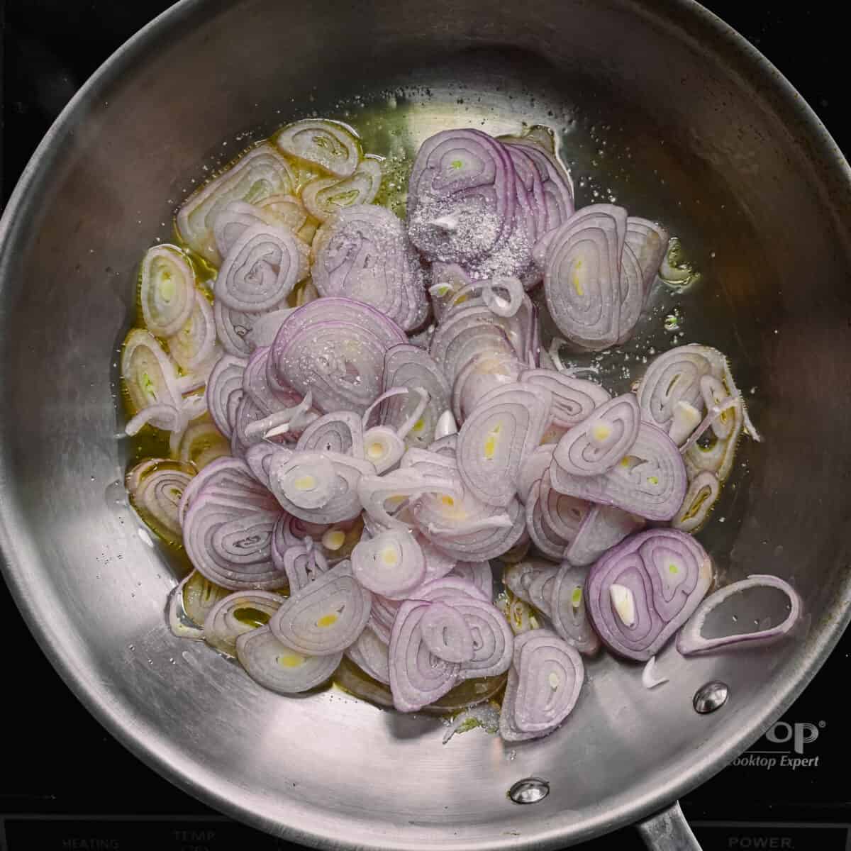 sliced shallots sauteing in olive oil in a skillet