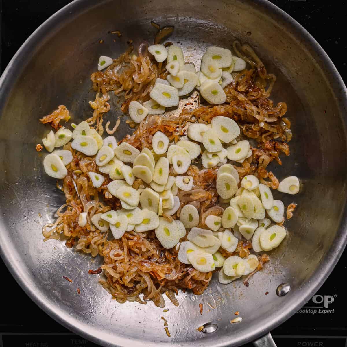 thinly sliced garlic cloves with caramelized shallots in a skillet