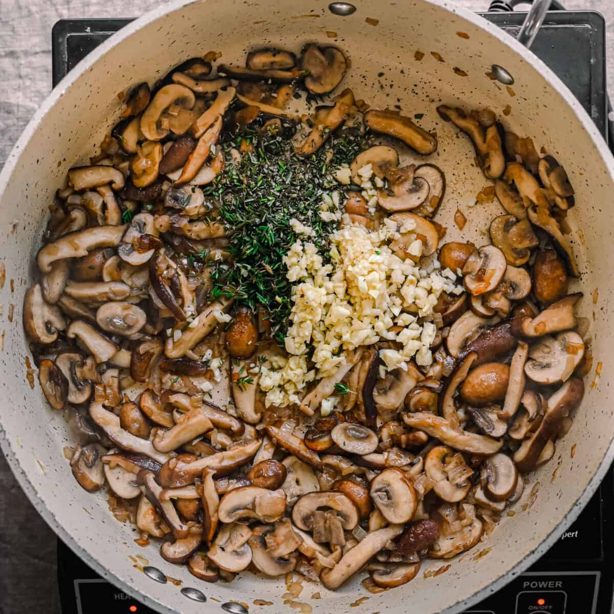 garlic, thyme, and rosemary added to sauteed mushrooms in skillet