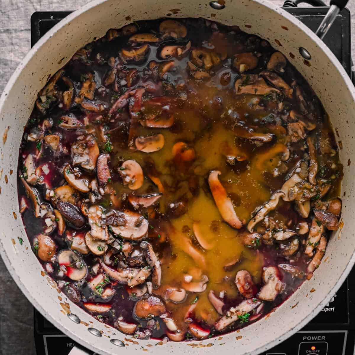 vegetable broth and wine in pan with mushrooms