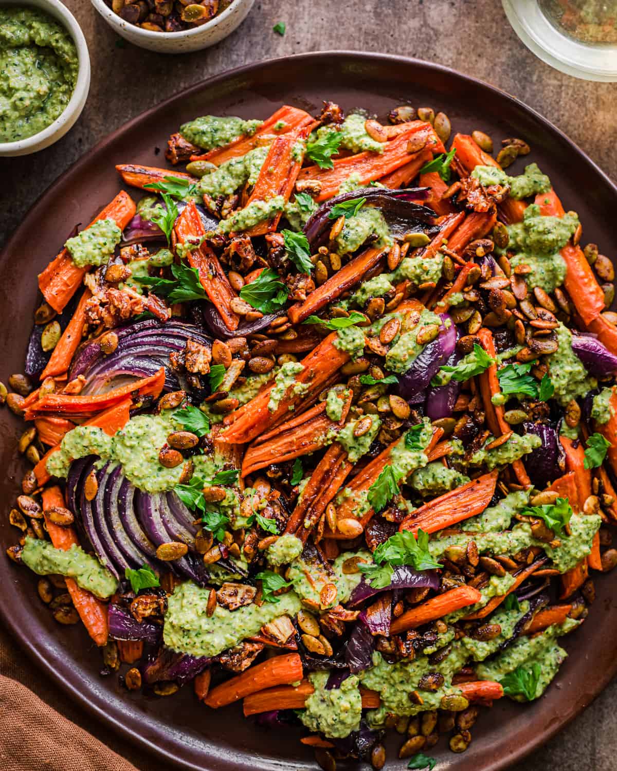 big plate of roasted carrots, red onions and dates covered in pesto.