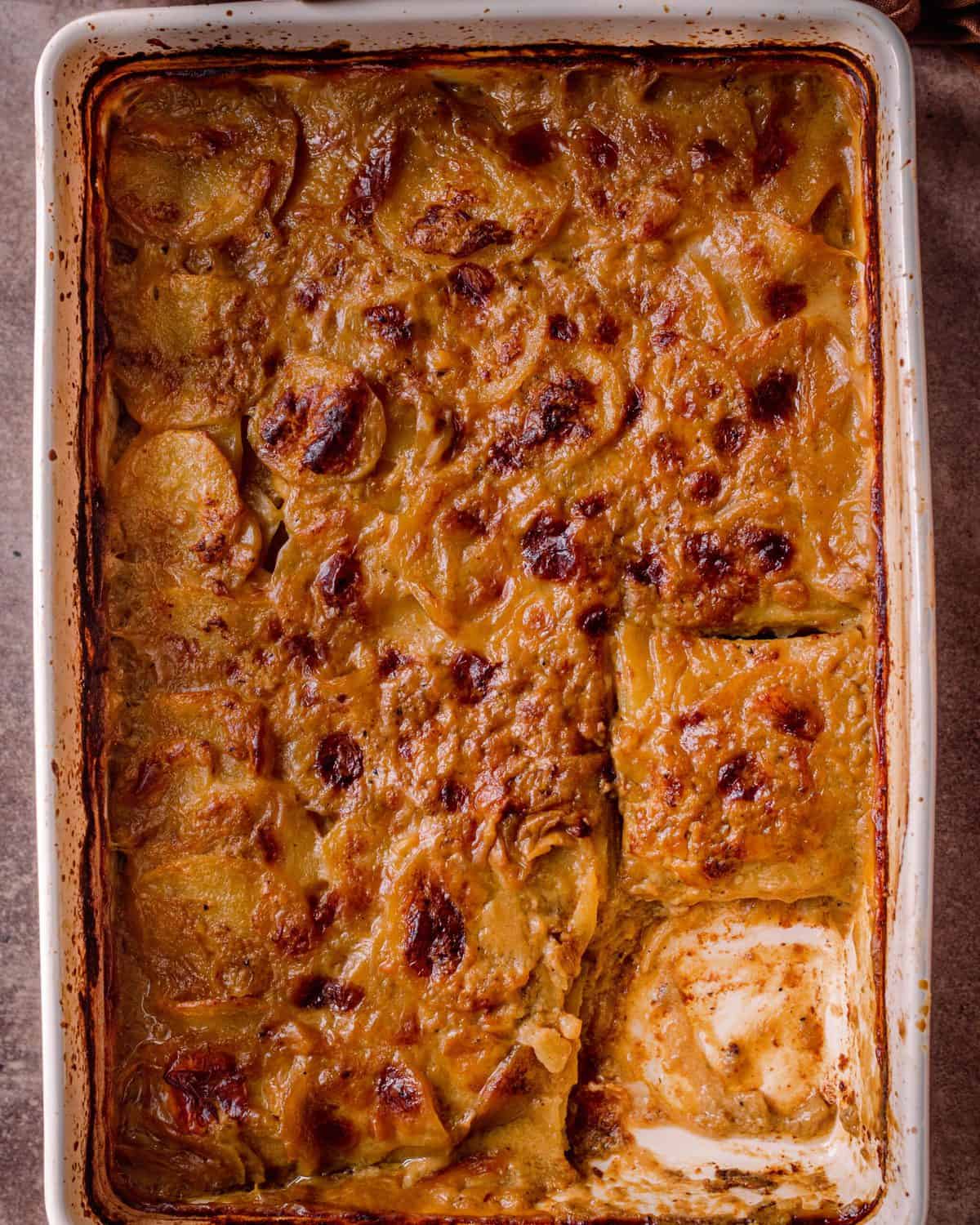 cheesy vegan scalloped potatoes in casserole pan with slice cut out