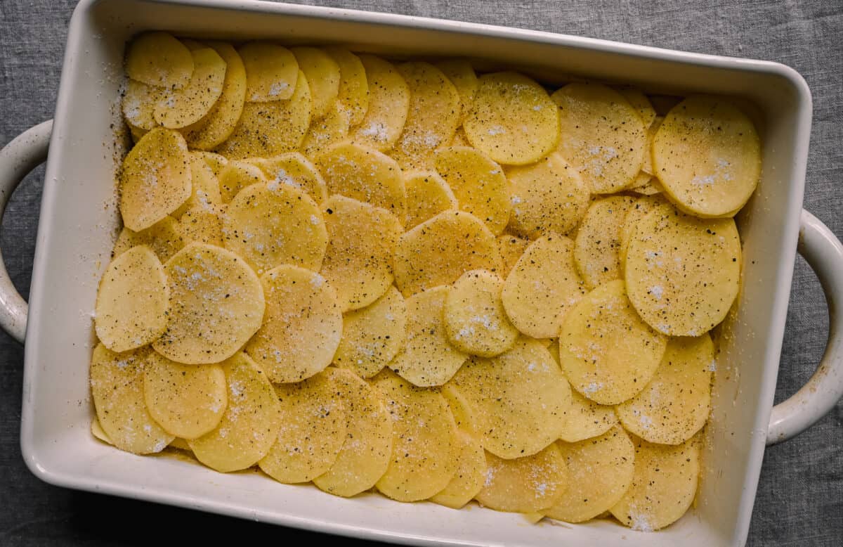 layers of thinly sliced potatoes in casserole dish for scalloped potatoes