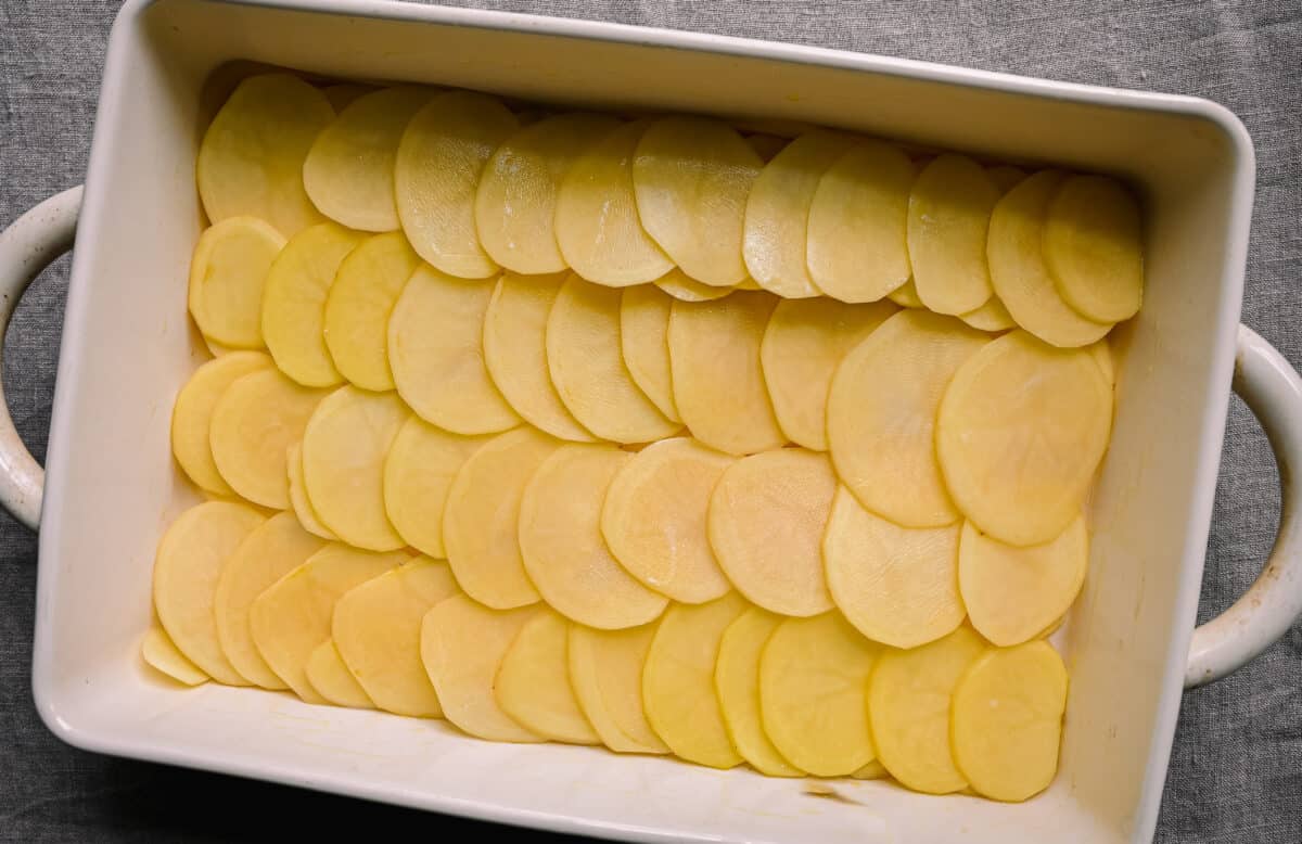 potato slices lined up in casserole pan for scalloped potatoes