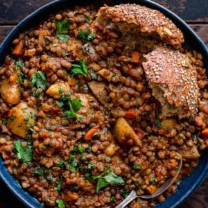 instant pot lentil soup in blue bowl with seeded bread on wooden table