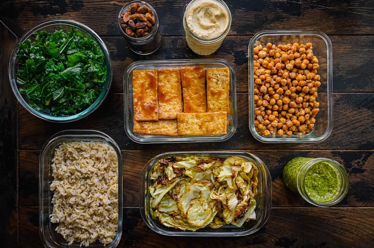 healthy vegan foods meal prepped in glass containers on a wooden table