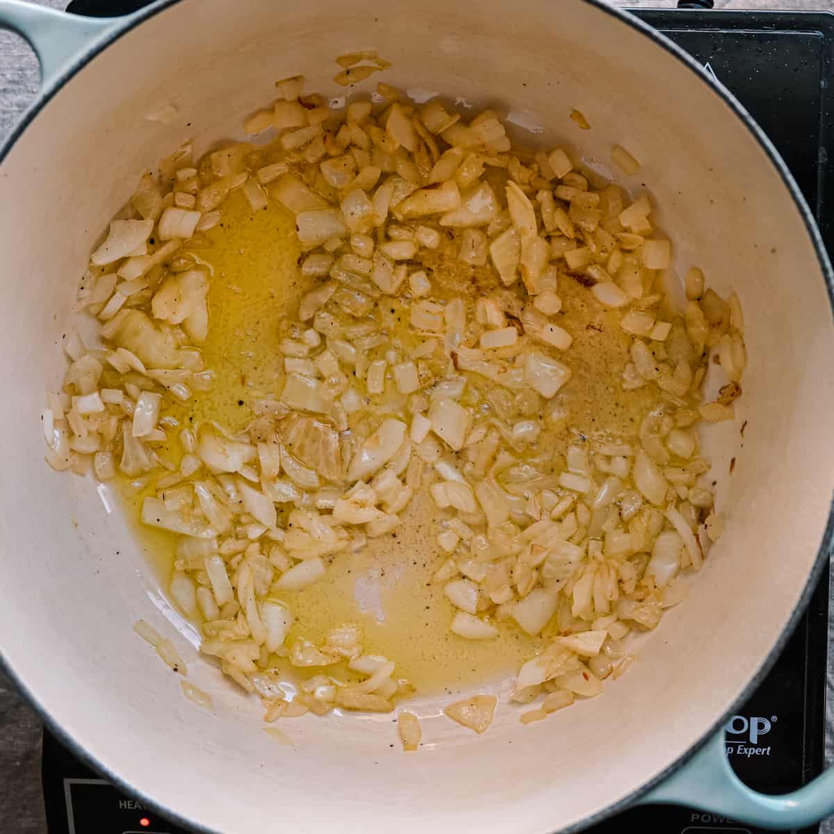 onions sauteing in olive oil in a dutch oven