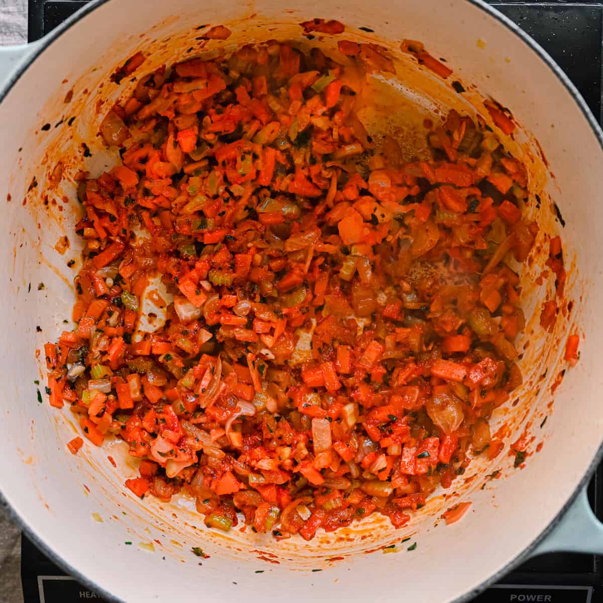 tomato paste cooking in onions and carrots in dutch oven