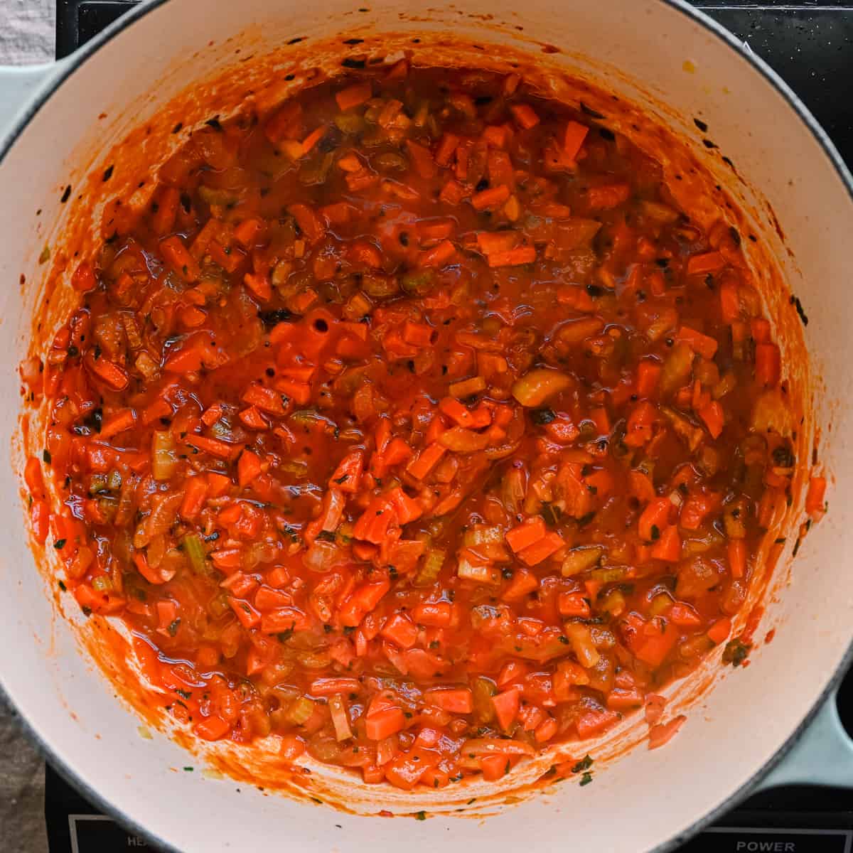 white wine simmering in tomato paste and carrots for italian stew