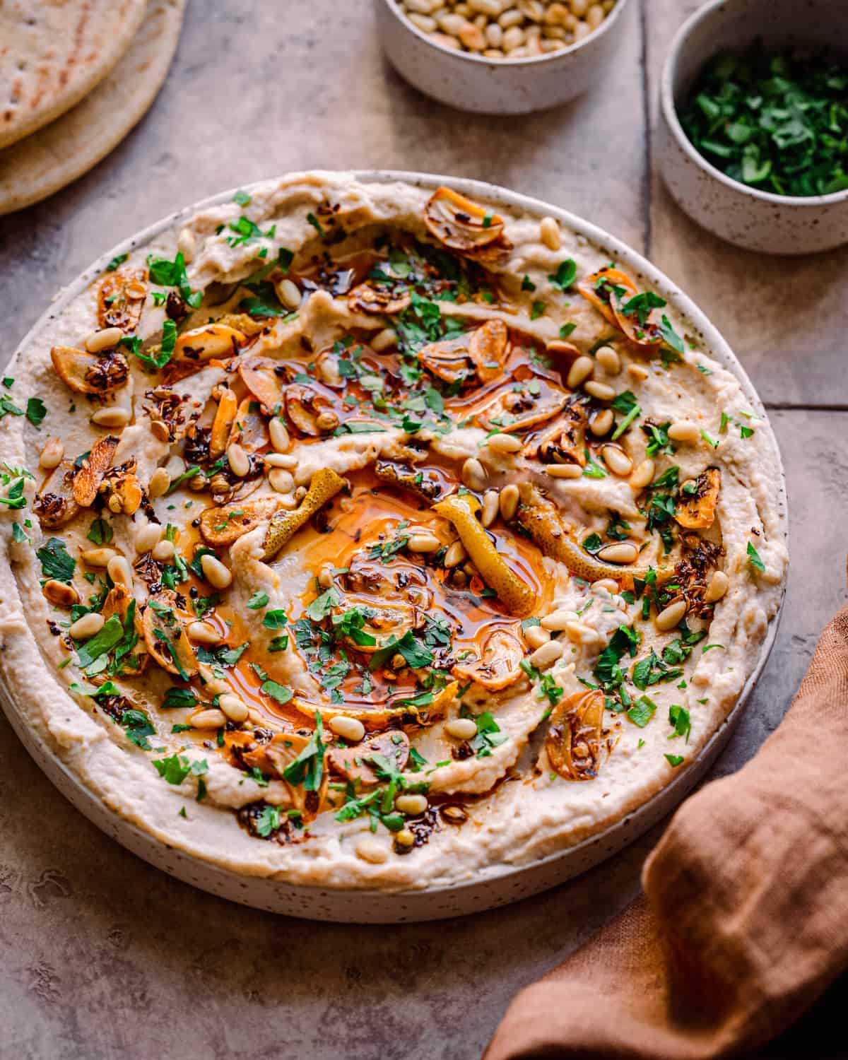 white bean dip with chili oil, garlic, parsley and pine nuts on tiled surface with pita bread