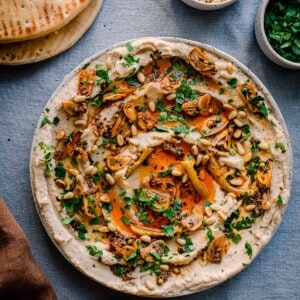 white bean dip with chili oil, garlic, parsley and pine nuts on blue tablecloth with pita bread