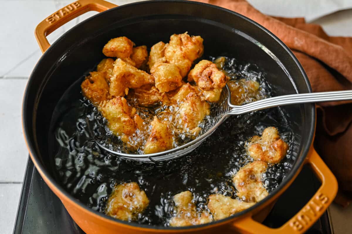 scooping fried cauliflower florets using a spider tool