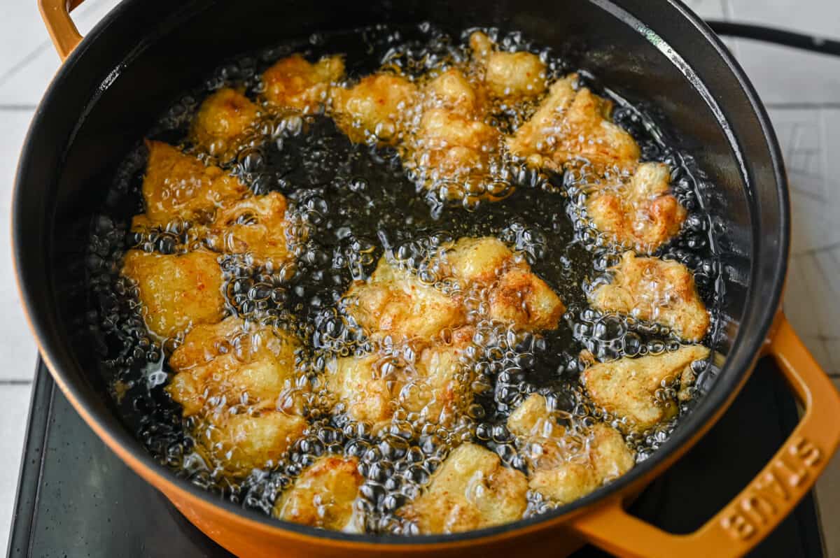 golden cauliflower florets sizzling in pan of hot oil