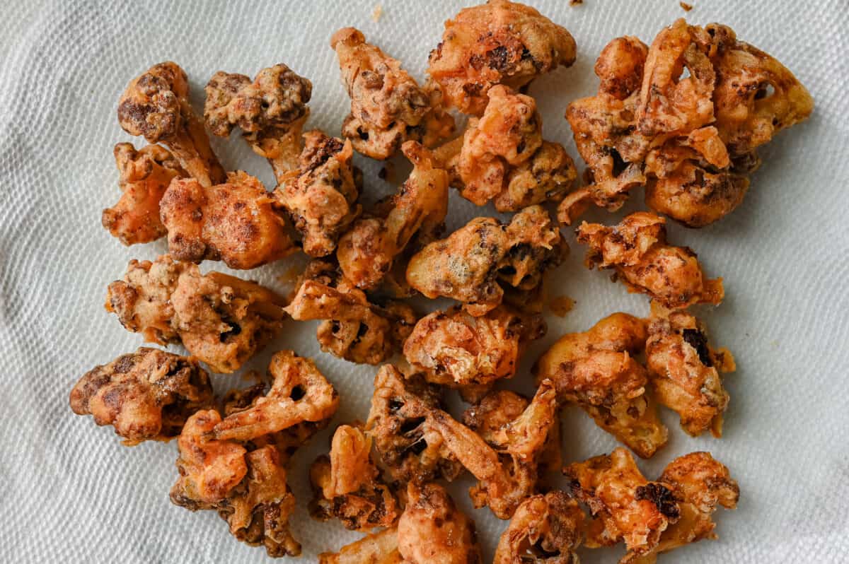 deep fried cauliflower florets on a paper towel