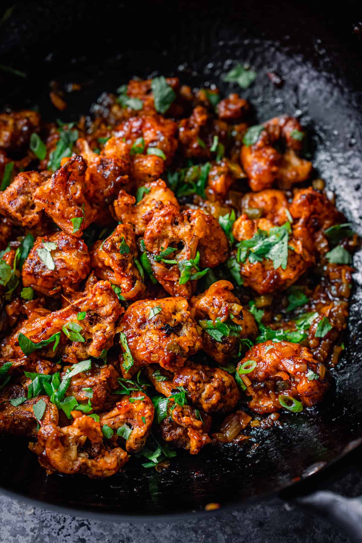 Gobi Manchurian in a wok, garnished with scallions and cilantro