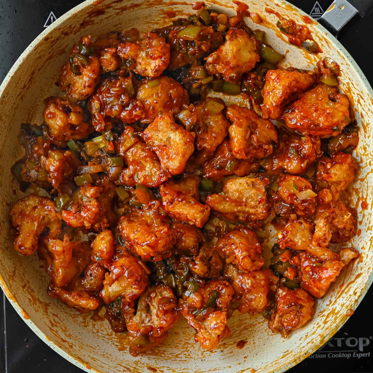 Fried cauliflower florets coated in MAnchurian sauce in a frying pan