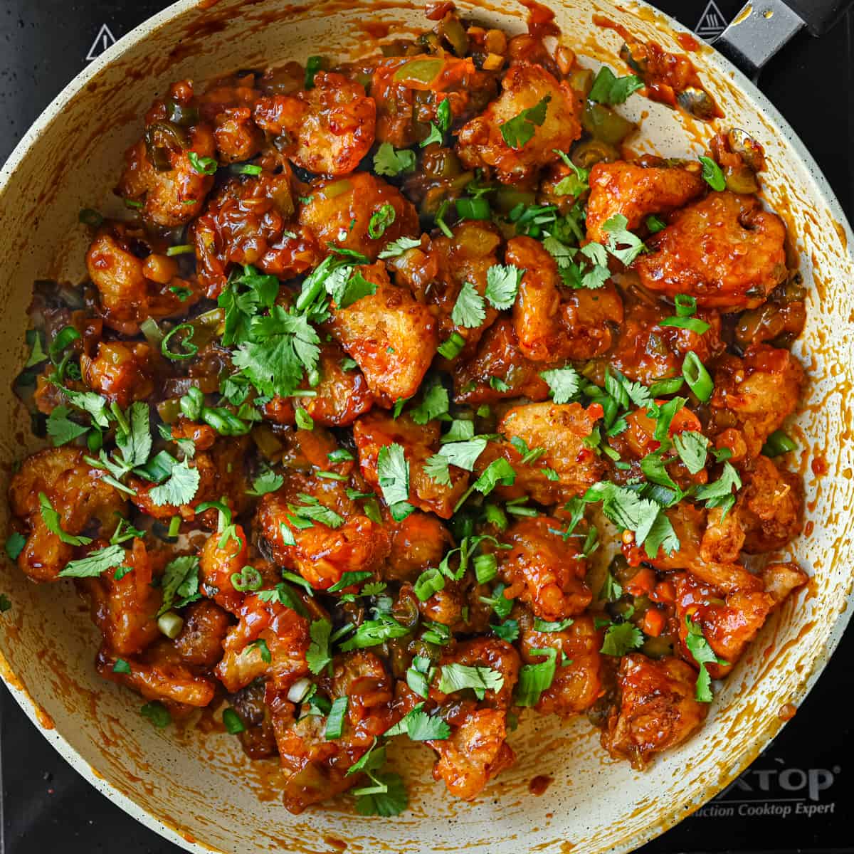 Gobi Manchurian in frying pan, garnished with scallions and cilantro