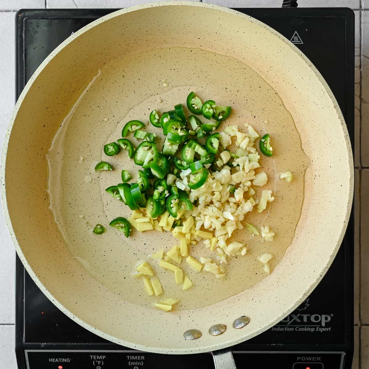 garlic, ginger, chili pepper in frying pan with oil
