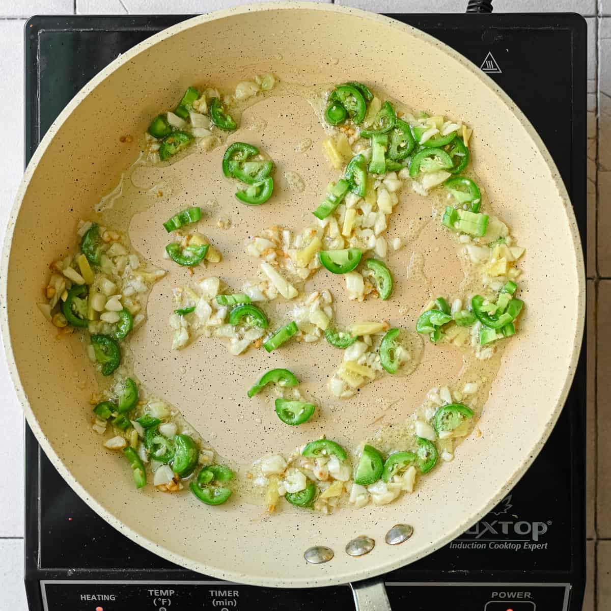 garlic, ginger, chili pepper sauteing in oil in frying pan