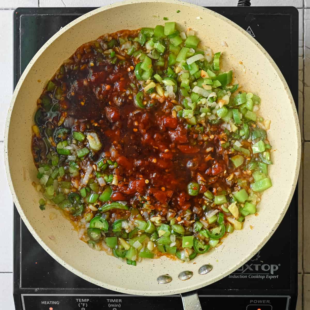 Manchurian sauce with scallions, shallots, green peppers, garlic and ginger frying in saute pan