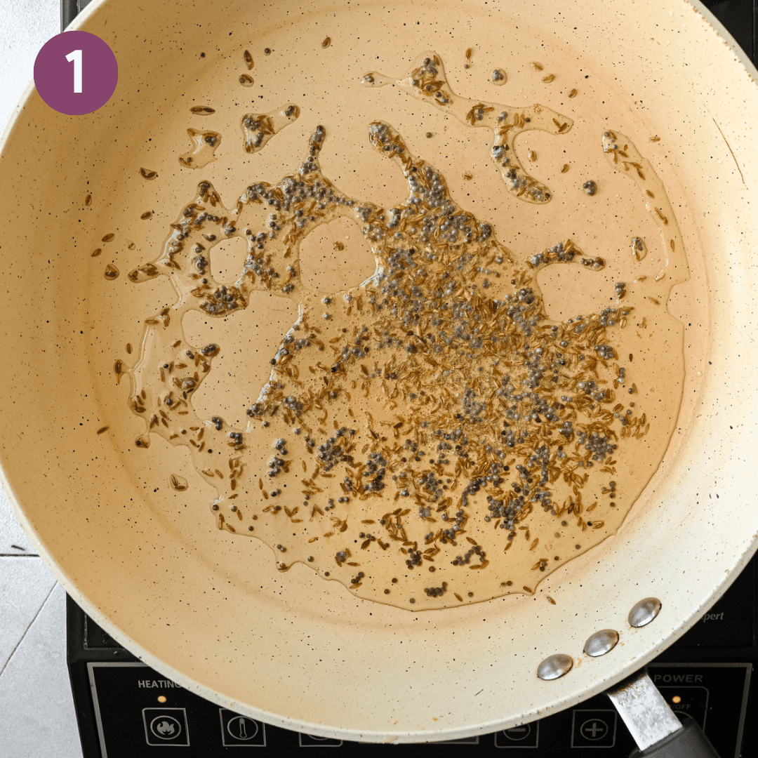 mustard seeds and cumin seeds frying in oil in a frying pan.