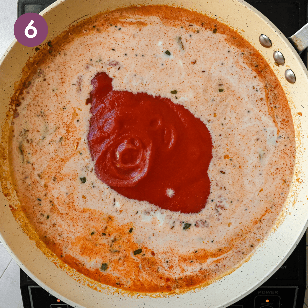 tomato sauce poured into a creamy Indian masala gravy in a saute pan. 